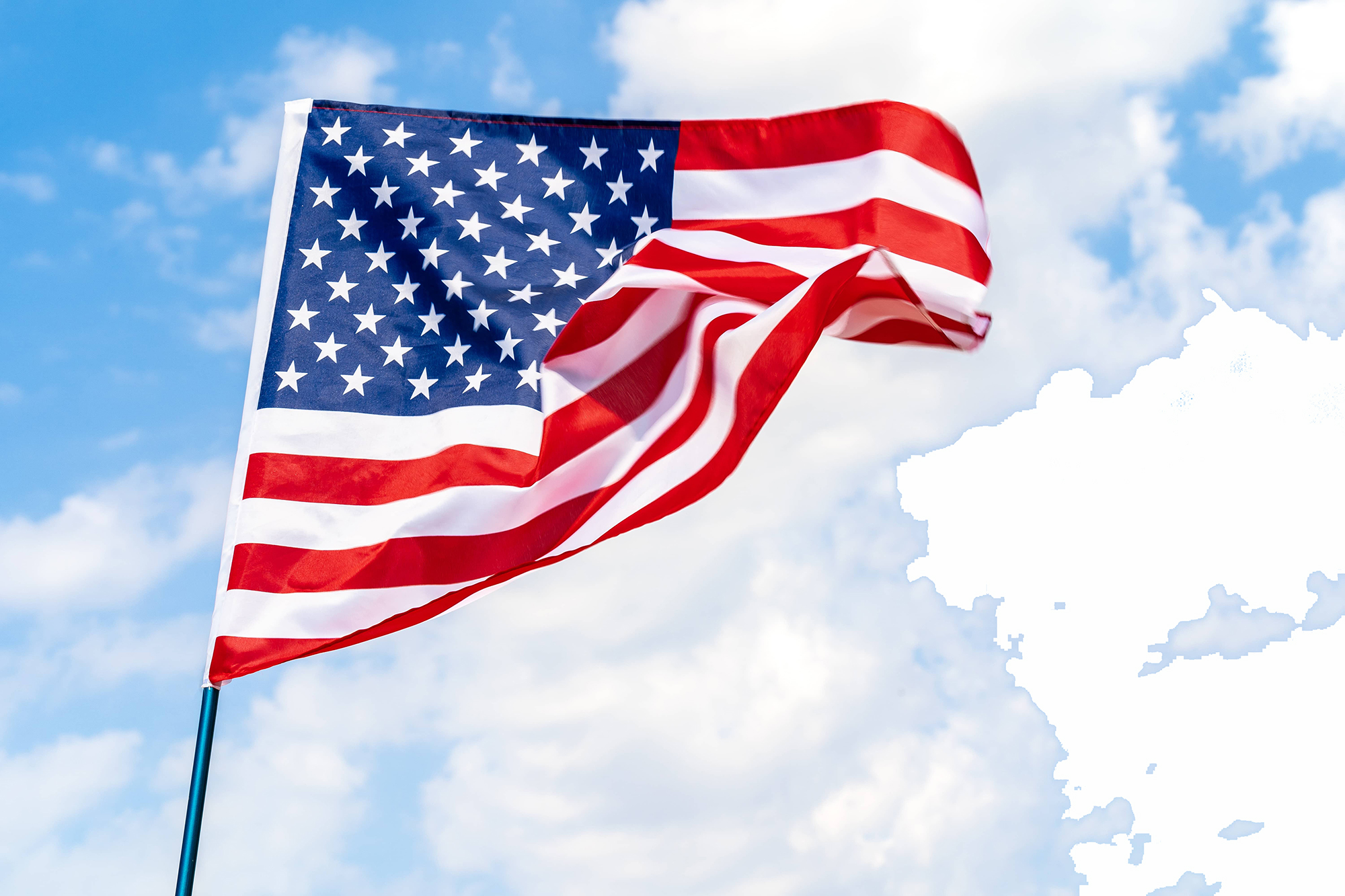The US flag blowing in wind in front of blue sky