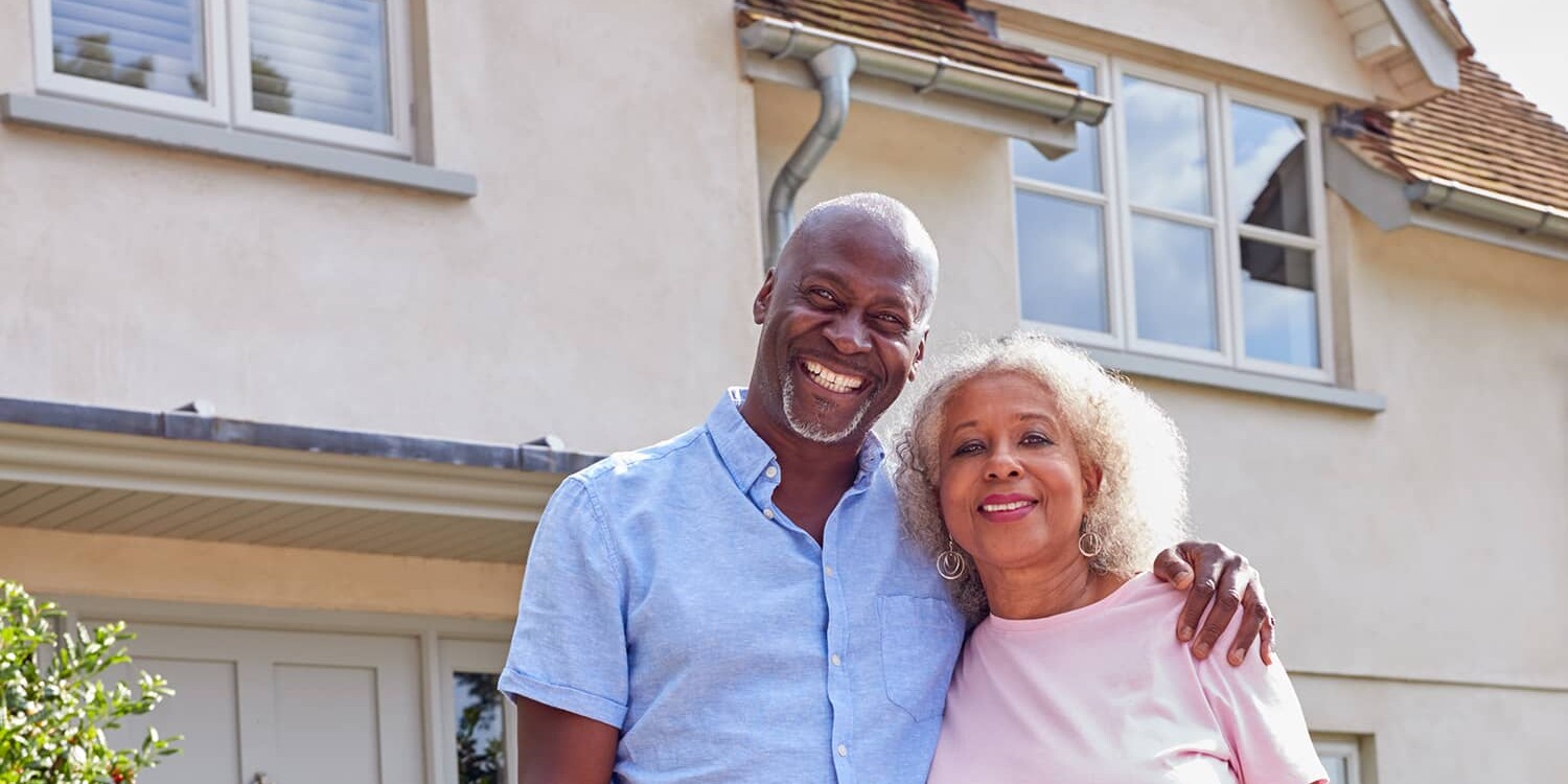 a couple standing outside of their home