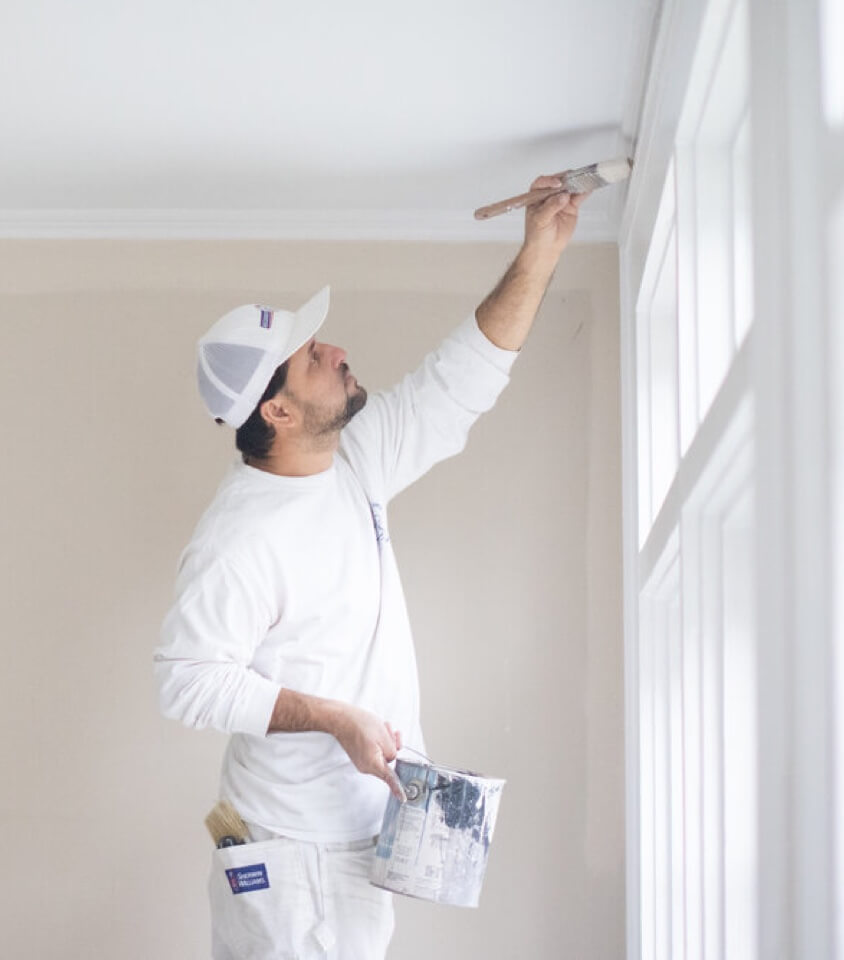 painter painting interior trim in a home
