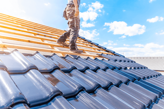 A man on a roof installing shingles